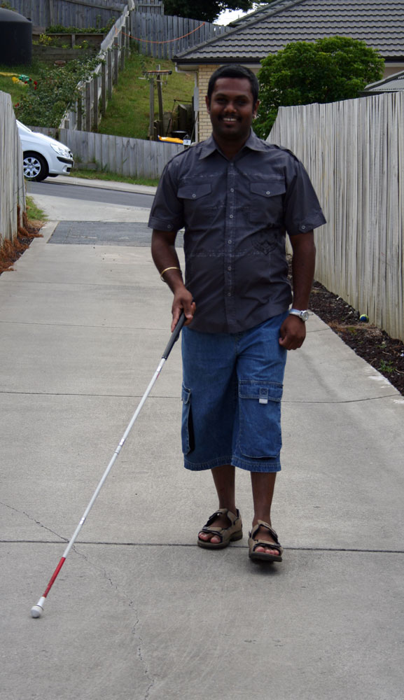 a man walking down the a driveway with a white cane